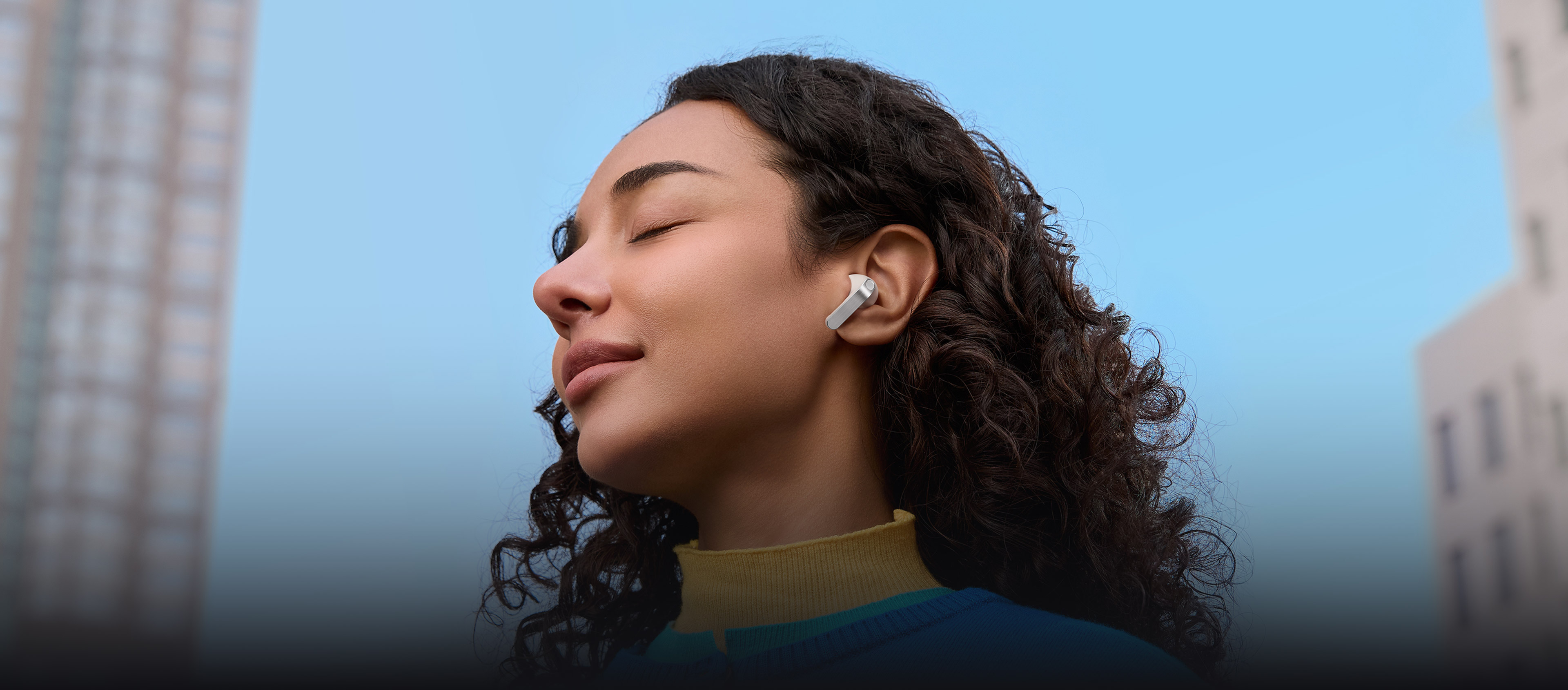 A woman with a single, white Galaxy Buds4 Pro earbud in her ear.