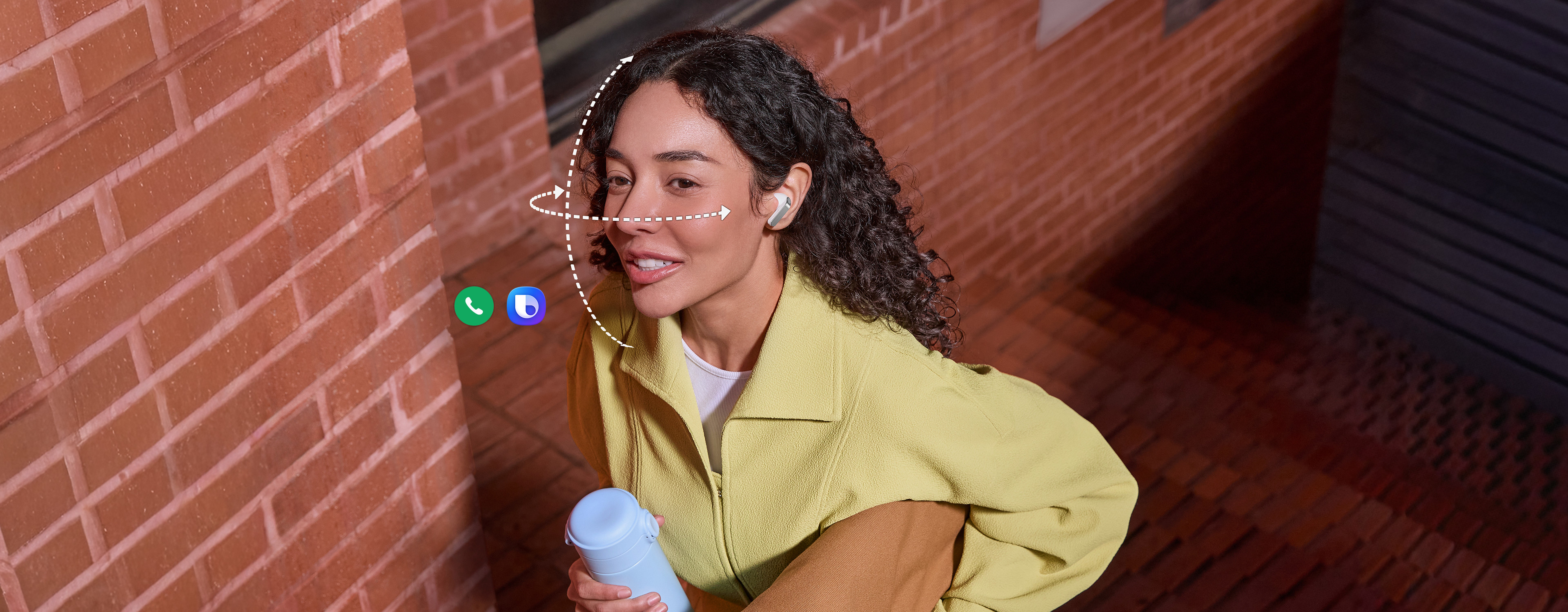 A person wearing Galaxy Buds4 Pro in White, while holding a tumbler in one hand and a bag in the other. Dotted vertical and horizontal lines wrap around her face to show the Head Gesture function available on the Galaxy Buds4 Pro. Call app icon and Bixby icon indicates the two features can be used for Head Gesture.